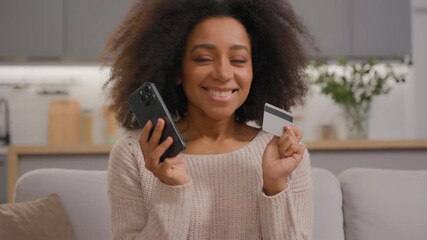 Happy joyful African American woman girl female shopping online at home with mobile phone and credit card bank service ordering food delivery purchasing goods with smartphone e-commerce app using - Powered by Adobe