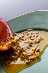 Fruit and juice spilling out of a halved passion fruit on a plate