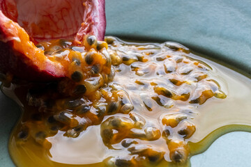 Fruit and juice spilling out of a halved passion fruit on a plate