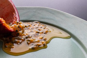 Fruit and juice spilling out of a halved passion fruit on a plate