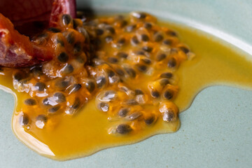 Fruit and juice spilling out of a halved passion fruit on a plate