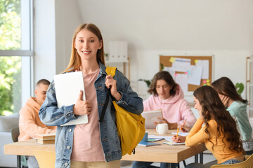 Female student with backpack and laptop in classroom