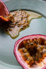 Fruit and juice spilling out of a halved passion fruit on a plate