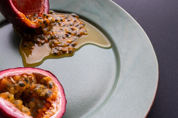 Fruit and juice spilling out of a halved passion fruit on a plate