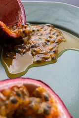 Fruit and juice spilling out of a halved passion fruit on a plate