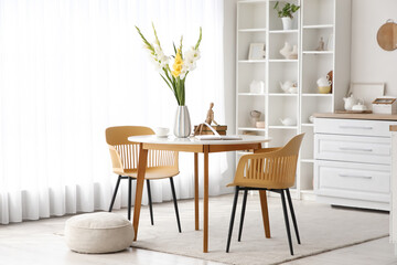 Vase with gladiolus flowers on dining table in kitchen interior