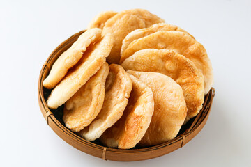 A woven basket filled with kerupuk kemplang, traditional Indonesian fish crackers, served on a white background.