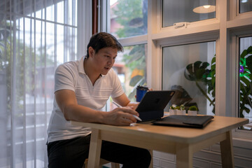 Asian freelancer working from home using tablet and stylus
