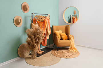 Interior of clothing store with rack, armchair and pampas grass