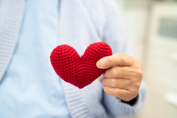 Asian elder senior woman patient holding red heart in hospital.
