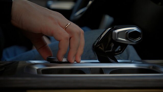 Driver adjusts gear shift while navigating a modern vehicle in an urban environment during daylight