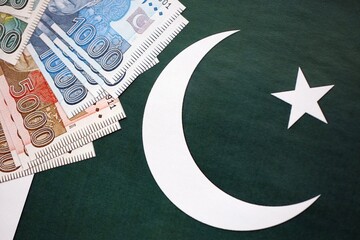 Pakistan rupees banknotes on Pakistani flag background. The current Pakistan money bills