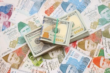 Bunch of US dollar bills lies on big amount of Pakistan rupees banknotes close up