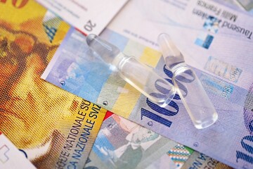 Swiss franc banknotes and medicine bottles. The current francs money bills and injection dose