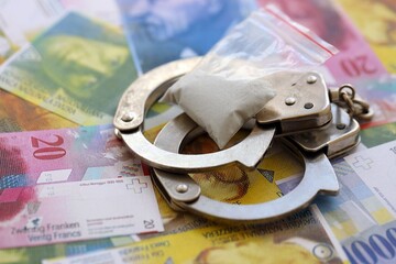 Swiss franc banknotes and cocaine pack with handcuffs. The current francs money bills and cuffs