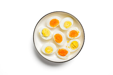 Overhead shot of assorted hard-boiled egg halves on a white plate, showcasing yolks from soft to...