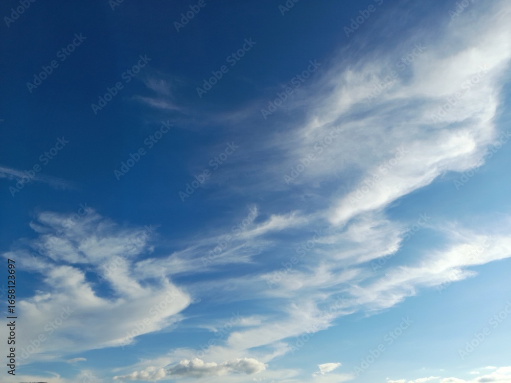 Wall mural the clouds in the photo are cirrus clouds that form high in the sky and have a feather or thread-lik