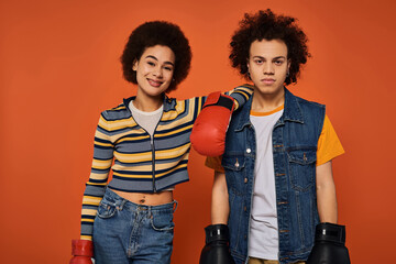 Young friends pose confidently with boxing gloves against a vibrant orange backdrop