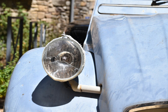 Vintage light blue Citro&euml;n 2CV parked near stone wall in a rustic European village, symbolizing retro lifestyle, French culture, and timeless automotive heritage.