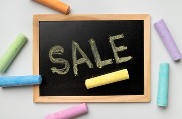 Black chalkboard in a wooden frame with the inscription Sale, multi-colored chalk on light...