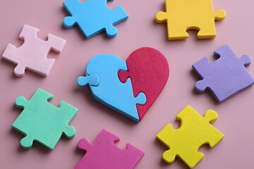 Colorful puzzle pieces in shape of heart on color background. Concept of autistic disorder
