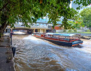 Fototapeta premium ferry boat going through a Canal Khlong in Thai running from Siam to Pathum Wan in BKK Bangkok Thailand. This is a preferred mode of transport in BKK due to traffic congestion 