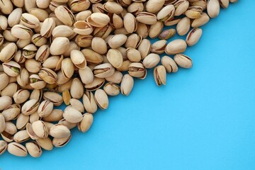 Tasty unpeeled pistachios on bright blue background, top view flat lay background pattern