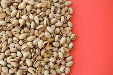 Tasty unpeeled pistachios on bright red background, top view flat lay background pattern