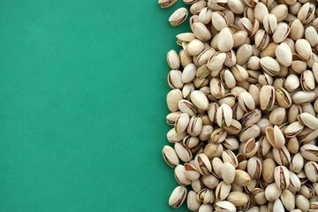 Tasty unpeeled pistachios on bright green background, top view flat lay background pattern