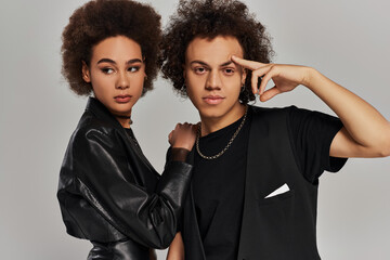 Young individuals with curly hair showcase modern fashion in a stylish studio setting