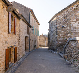 Narrow streets of Minerve, Occitanie, France, with medieval stone buildings in light beige and...