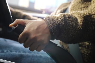A woman pulls the handbrake in an automatic transmission car.