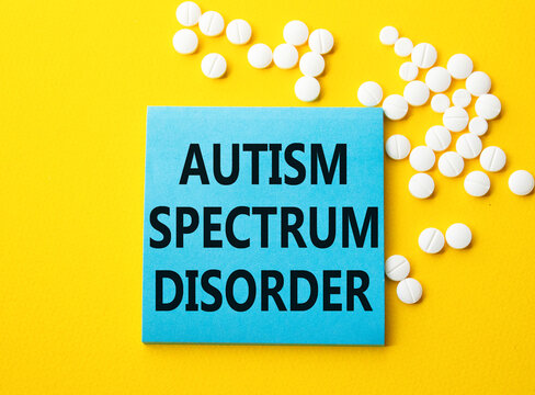 Autism Spectrum Disorder symbol. Concept word Autism Spectrum Disorder on blue note. Beautiful yellow background with pills. Medicine and Autism Spectrum Disorder concept. Copy space
