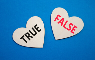 True or False symbol. Concept word True or False on wooden hearts. Beautiful blue background....
