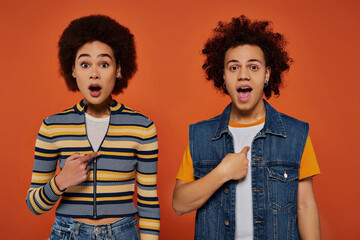 Expressive young friends showcase colorful fashion against vibrant orange backdrop