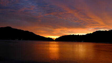 Colorful sunset over tropical islands with orange and purple sky reflecting on the calm sea in Raja...