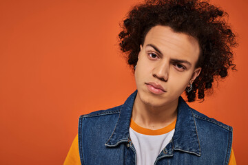 Vibrant fashion style highlighted by a young person with curly hair against an orange wall