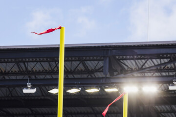 wind streamers are seen on top of the football field goal post inside a stadium.
