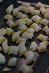 A batch of uncooked potato gnocchi sits on a baking sheet, ready to be prepared in a kitchen setting.