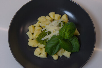 A close-up shot of green pesto made with pistachios and fresh basil in a clear glass on a kitchen countertop.