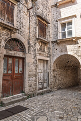 Journey back in time through a deserted medieval street in Europe, with ancient stone architecture and weathered, rustic doorways.The weathered facade of an ancient stone building in a medieval city