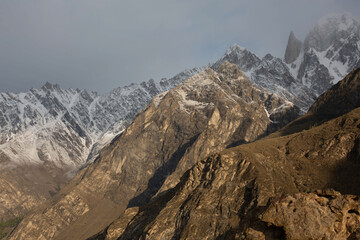 Jagged rocky mountain range with snow-dusted peaks and steep ridges under a moody overcast sky.
