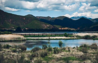 Aerial view of serene Lugu Lake with wooden bridge and majestic mountains, Xichang China - natural...