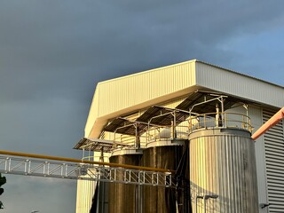 industrial building with silo. An outdoor industrial facility features a large, weathered tank...