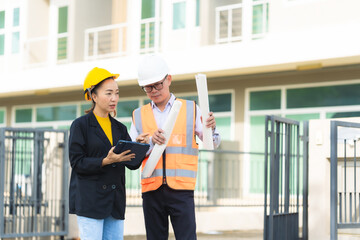 Female architect or engineer with blueprints at construction site, teamwork discussion, Caucasian...