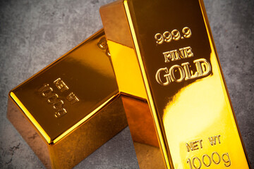 Gold bullion bars on grey stone background, closeup. Financial concept