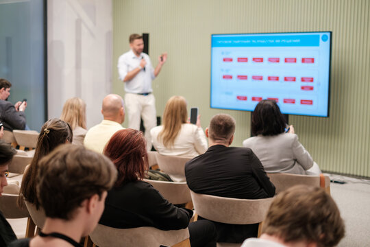 Professional speaker presents training session to audience in modern business seminar setting