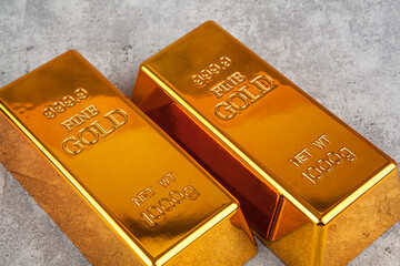 Gold bullion bars on grey stone background, closeup. Financial concept