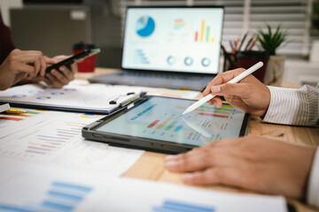 A corporate team collaborates in an office, analyzing financial reports and charts. They discuss strategy, investment, and planning to achieve growth, innovation, success, and long-term business perfo