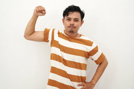 Young Asian man in white and brown striped shirt flexing his arms and shouting with intense facial expression, conveying power or anger, against white background